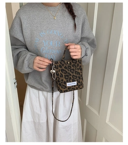 Close-up of a leopard print crossbody bag featuring a heart pendant and brand label