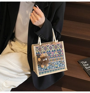 Detailed close-up of a small ethnic tote bag with colorful patterns and furry keychain