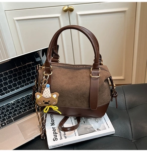 Detail of dark brown boston bag with suede拼接 finish and cute plush bear accessory