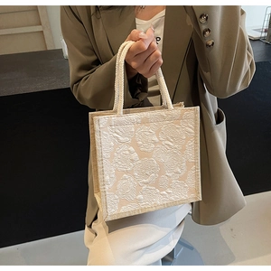 Detail of apricot tote bag with embossed rose pattern and woven cotton rope handles