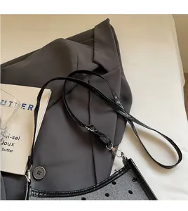 Detail of adjustable black leather strap and silver metal buckle on polka dot shoulder bag