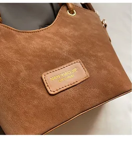 Macro detail of brown leather bucket bag showing fine texture and metallic ring hardware