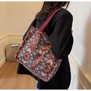 Detail of colorful geometric jacquard weave and wide red shoulder strap on tote bag