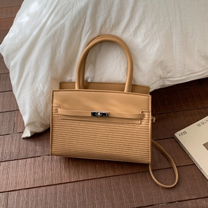 Detail of trendy patchwork handbag featuring textured weave, leather handles, and metal clasp