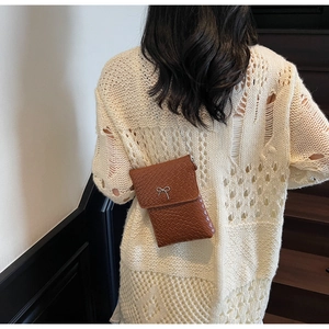 Detail of brown woven texture crossbody bag with silver bow buckle on model