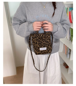 Detail of trendy leopard print mini crossbody bag with rectangular brand patch and handle