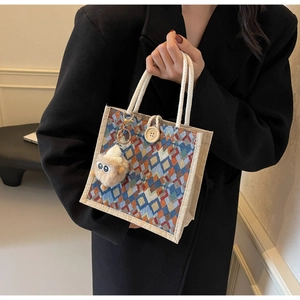 Detail of woven lattice tote bag featuring geometric pattern and monster plush charm