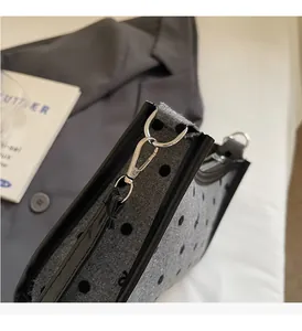 Detailed macro view of silver lobster clasp and D-ring on grey polka dot shoulder bag