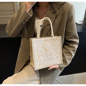 Detail of off-white jacquard tote bag with woven rope handle and floral texture