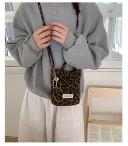 Leopard print crossbody bag detail shown on a model with metallic heart and chain charms