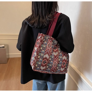 Close-up of ethnic tote bag showing dark red geometric jacquard fabric and woven strap