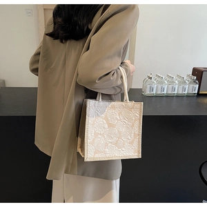 Detailed shot of beige floral jacquard tote bag with white cotton rope braided handle