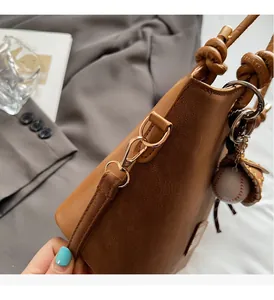 Close-up of brown bucket bag with lychee texture leather and gold metal hardware detail