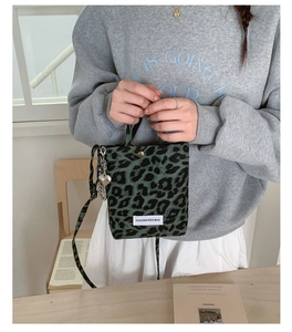 Detail of green leopard print mini crossbody bag with heart charm and shoulder strap