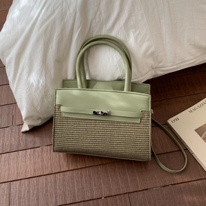 Detail of light green handheld bag featuring woven texture and metal turn-lock closure