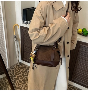 Detail of vintage brown leather boston bag with suede stitching and cute bear charm