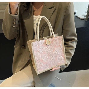 Detail of pink jacquard handbag with woven rope handles and vintage wood button closure