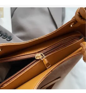 Detail view of smooth golden metal zipper closure on the brown leather bucket bag