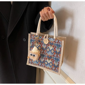Detail of geometric woven handbag with wooden button and cotton rope handles