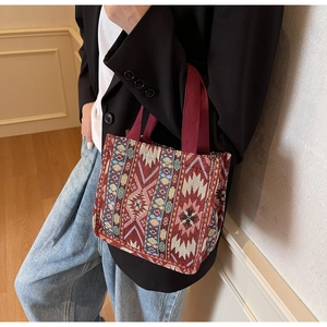 Ethnic tote bag with red geometric pattern and canvas texture shown in lifestyle use
