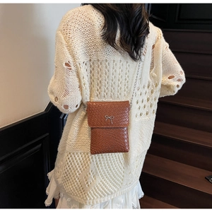 Macro detail of brown woven texture handbag with silver bow metal buckle and chain strap