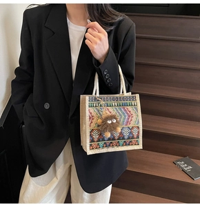 Close-up of woven geometric patterns and plush monster charm on a stylish handbag