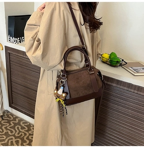 Deep brown Boston bag detail showing suede stitching, leather texture and bear charm