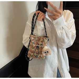Détail du sac à bandoulière tissé avec motifs géométriques et breloque monstre en peluche