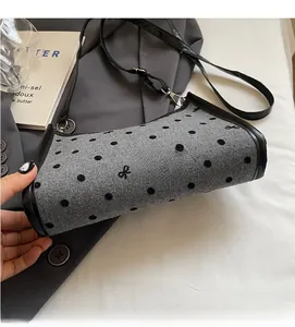 Close-up of gray polka dot felt bag with black bow embroidery and fine fabric texture