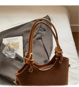 Detail view of brown textured leather bag with knotted handle and golden metal accents