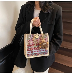 Stylish woven geometric pattern tote bag with decorative button and monster charm