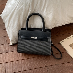 Detail of black patchwork handbag featuring woven texture and silver metal twist lock