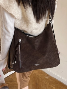 Modische dunkelbraune Wildleder-Schultertasche mit Reißverschluss an einem Modell