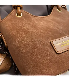 Close-up of brown lychee grain leather bucket bag with gold ring hardware and logo tag