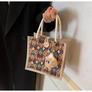 Detail of checkered linen tote with cotton handles, wooden button, and plush pendant