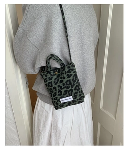 Detail view of mini leopard print crossbody bag with bronze snap button and thin strap