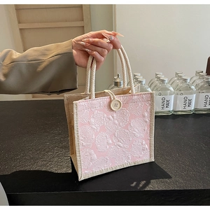 Detail of pink floral jacquard handbag with embossed rose patterns and rope handles