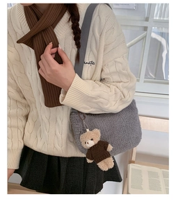 Détail d'un sac bandoulière en peluche grise avec un charmant petit ours en peluche