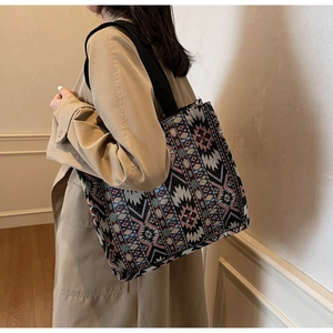 Close-up of woven tote bag with colorful ethnic geometric patterns and black strap