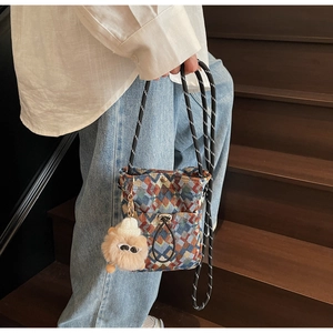 Détail du sac bandoulière bohème tissé à motifs géométriques avec breloque d'ours en peluche