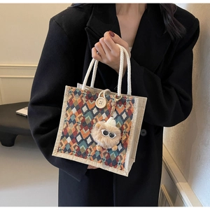 Detail of rhombic patterned linen handbag with a plush charm and decorative button