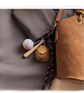 Detail of baseball sports keychain set with bat and glove on a brown leather bucket bag