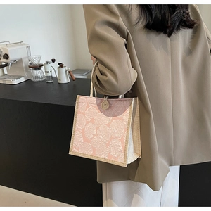 Detail of pink embossed rose pattern on a handbag with rope handles and beige trim