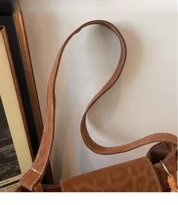 Close-up of brown suede strap with white stitching and subtle leopard embossing on the bag