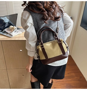 Rear view of a woman wearing a canvas and brown leather Boston bag in an office setting
