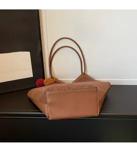 Detail of large brown leopard tote bag with plush pompom charms on a black display stand