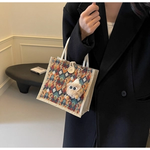 Detail of colorful geometric lattice tote bag with white rope handle and plush doll charm