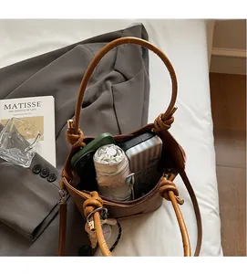 Detail of a brown leather bucket bag with knot handle showing ample interior storage space