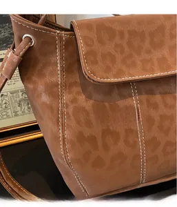 Detail of vintage brown bucket bag with leopard texture and white contrast stitching