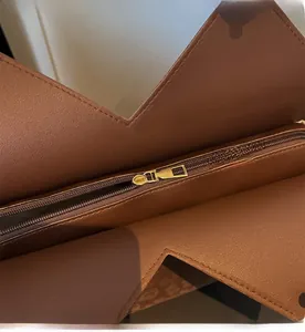 Close-up of smooth gold metal zipper and stitching on brown leather tote bag